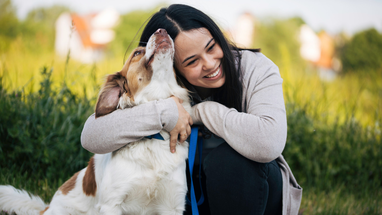 Eine Frau kuschelt mit ihrem hypoallergenen Hund in der Natur.